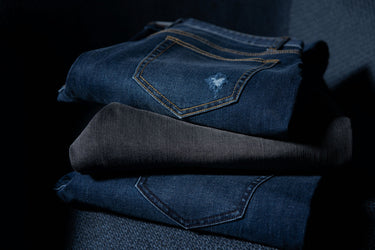 Stack of folded blue jeans on a dark background
