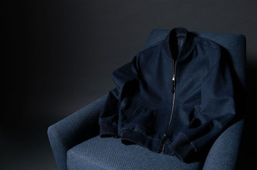 Navy blue jacket on a dark gray chair against a black background