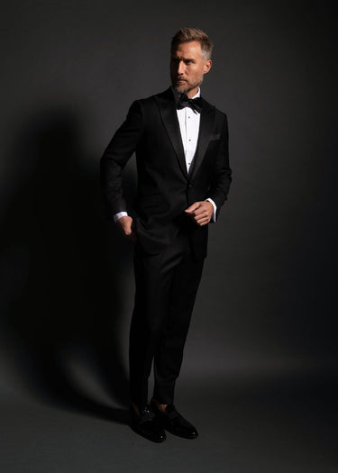 Man wearing a black tuxedo against a dark background