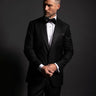 Man wearing a black tuxedo against a dark background