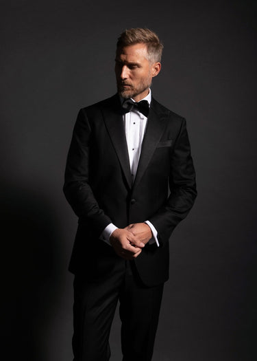 Man wearing a black tuxedo against a dark background