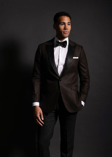 Man wearing a black tuxedo with a bow tie against a dark background