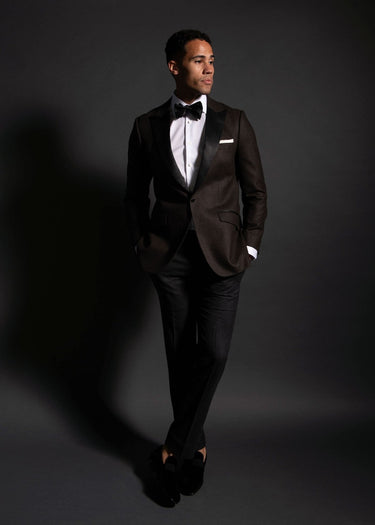 Man wearing a black tuxedo with a white shirt and bow tie on a dark background